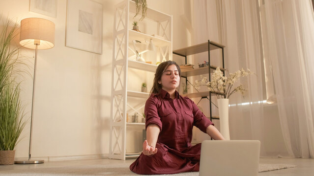 Yoga online. Meditation instructor. Mindful leisure. Woman coach teaching mudra gesture at laptop internet video call course at home in living room. - Powered by Adobe