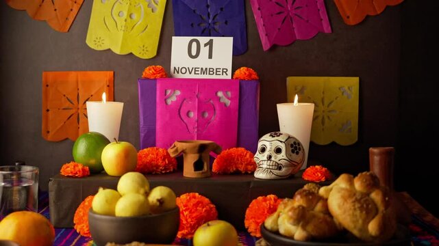 The hand of a mexican woman places a sign with the date November 02 on a offering of dia de muertos in mexico
