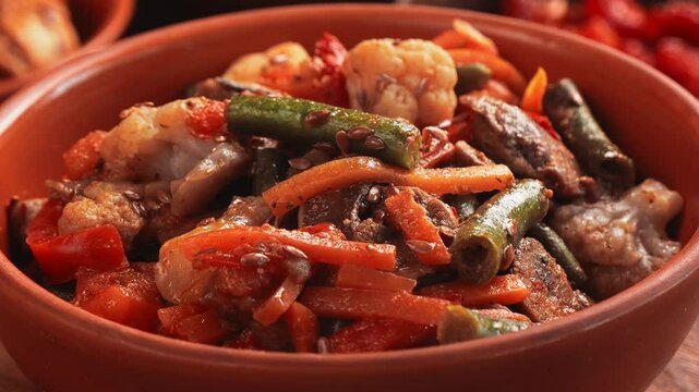 Vegetables beans broccoli mushrooms stewed with spices in a clay bowl rotates in a circle. Close-up