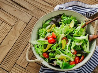 Healthy assorted vegetable salad with avocados and tomatoes, served in a bowl with diced cheese and an option of olive oil
