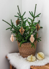 Fir branches with paper craft toys in a basket on a fluffy blanket in the living room