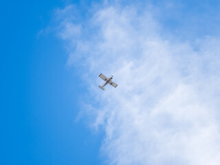 Small ultralight airplane with overhead wing and single propeller flying in sunset sky.