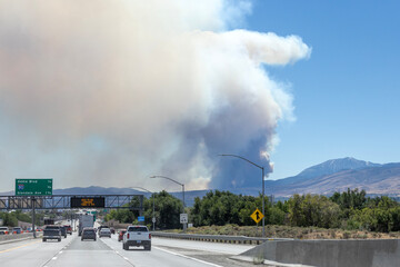 Plume of wildfire smoke from Davis fire south of Reno in the background of a freeway sign warning...