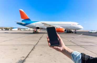 Girl holds a smartphone with a black screen close-up. Phone on the background of the airport with an airplane