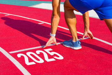Athlete runner in a pose ready to start on a red treadmill line with the inscription numbers 2025....