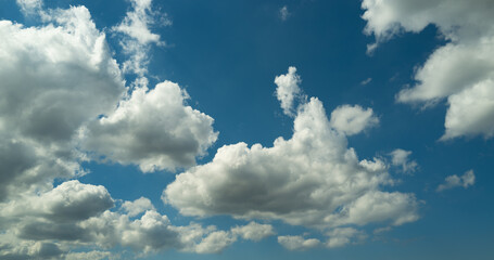 Sun shining through the puffy clouds. White clouds banner. Beautiful clouds. Background with clouds on blue sky. Summer Cloud on blue sky.
