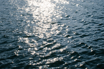 Sunset Reflections, Rippling Water Surface with Golden and Blue Hues at Evening sea wave abstract texture sunlight blue and golden pattern blurred background.