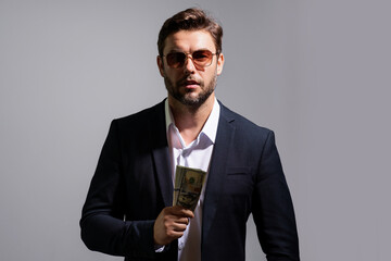 Man holding cash money in dollar banknotes on gray. Studio portrait of businessman with bunch of dollar banknotes. Dollar money concept. Career wealth business. Cash dollar banner.
