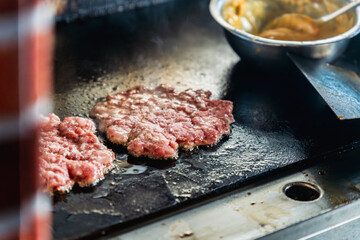 cooking smash beef patties on a flat grill