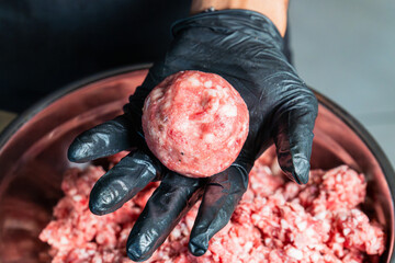 a chef forming a ball of ground beef patty by hand