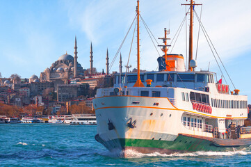 Obraz premium Cityscape of Istanbul with the Golden Horn and Suleymaniye Mosque - Water trail foaming behind a passenger ferry boat in Bosphorus on the background - Istanbul, Turkey