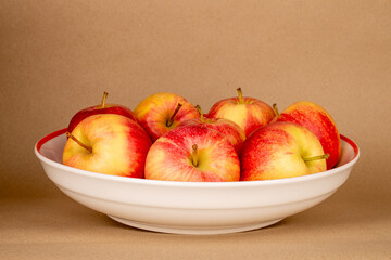 Several red apples on a ceramic plate on kraft paper, macro.