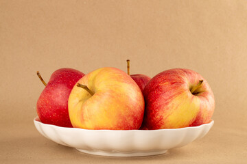Several red apples on a ceramic plate on kraft paper, macro.