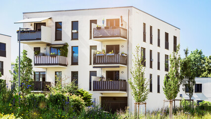 Modern Residential Building Apartment Exterior with Green Landscaping in Germany Munich. Modern Facade of Low rise Multi Storey Building with Flat Roof, Balcony Terrace and Urban Garden.