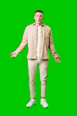 Confused Young Man Standing Against Bright Green Background With Open Arms in Uncertain Gesture