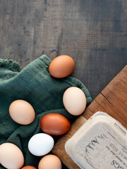 Brown and white eggs on green fabric beside carton
