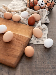 Eggs on a wooden cutting board and patterned cloth, with a wire basket