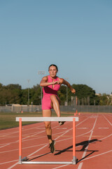 Obraz premium Female track athlete about to go over hurdle on track