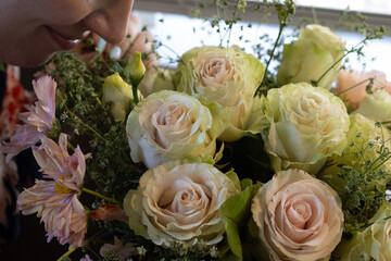 Woman smelling a fresh bouquet of roses and mixed flowers