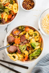 Bowls of tortellini with sausage, broccoli, carrots, and cheese