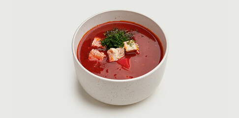 A bowl of traditional Ukrainian borscht is presented on a beige plate against a clean white background.