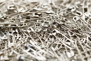 A number of stainless safety pins on white background.