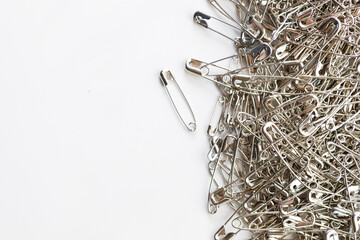 A number of stainless safety pins on white background.