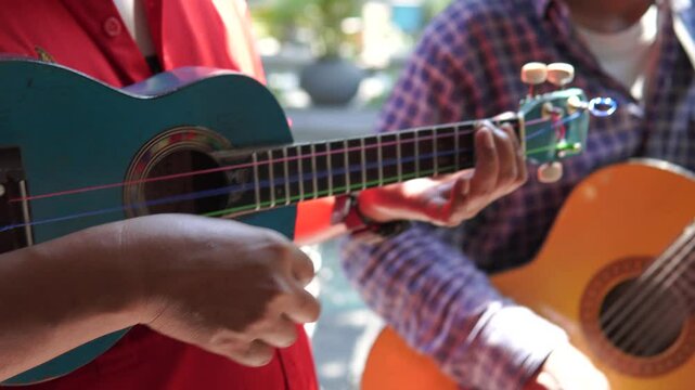 Busker group of men playing ukulele music instrument to entertain people.