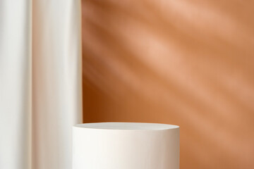 Minimalist decor featuring a white cylinder and draped fabric in a warm-toned interior with soft...