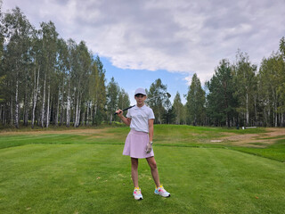 Teenager child practicing golf swing on a lush green course