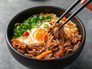 A vibrant bowl of savory beef bibimbap topped with a perfectly cooked egg and fresh vegetables