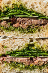 Close-up of a roast beef sandwith with salad and sun dried tomatoes on sourdough bread