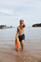 Alert Asian Lifeguard on Summer Beach, Man Saving Lives with Lifebuoy in Vibrant Coastal Scene