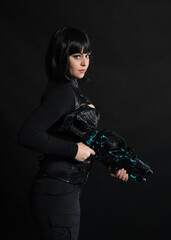 Naklejka premium Close up portrait of beautiful black female model wearing black sci fi futuristic dystopian leather bodysuit costume. holding gun weapon. isolated dark studio background moody silhouette.