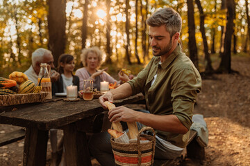 Father is breaking bread for his family during a picnic