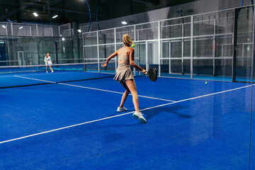 Blonde female padel player mid-motion during a match