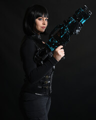 Close up portrait of beautiful black female model wearing black sci fi futuristic dystopian leather bodysuit costume. holding gun weapon. isolated dark studio background moody silhouette.