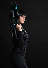Obraz premium Close up portrait of beautiful black female model wearing black sci fi futuristic dystopian leather bodysuit costume. holding gun weapon. isolated dark studio background moody silhouette.