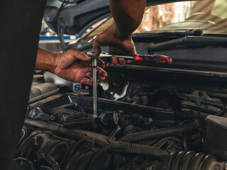Close up Car Mechanic man hands repairing car auto repair shop. Man hands fixing machinery vehicle...