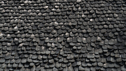 Close-up of weathered gray wooden shingles creating a textured roof pattern, conveying rustic and vintage charm.