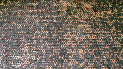 Close-up view of a tiled surface with a textured, intricate pattern of small circular tiles in various shades of brown and black.