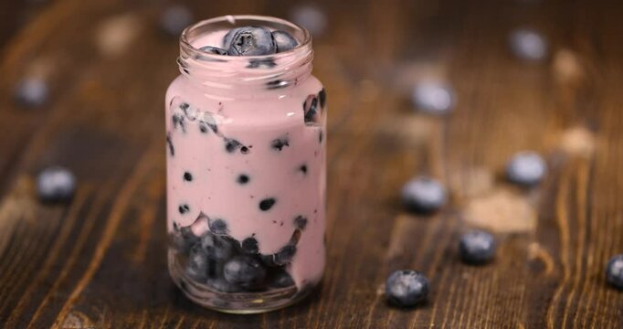 ripe blueberry berries with blueberry-flavored yogurt, delicious blueberry-flavored yogurt in a glass jar