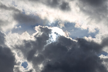 Darker dramatic clouds and sunlight beams at blue sky, capture from seaside
