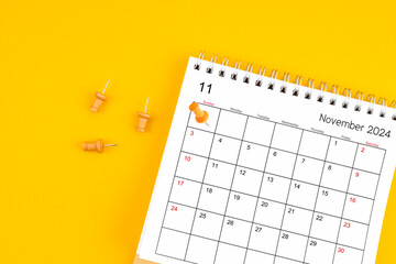 November 2024 Monthly desk calendar for 2024 year with wooden pin on yellow background.