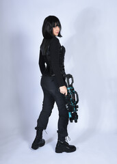 Naklejka premium Full length portrait of beautiful black female model with short black hair wearing sci fi futuristic dystopian leather bodysuit costume. Standing walking pose, isolated white studio background.