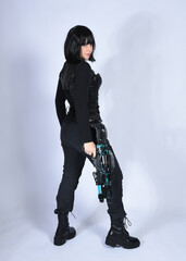 Naklejka premium Full length portrait of beautiful black female model with short black hair wearing sci fi futuristic dystopian leather bodysuit costume. Standing walking pose, isolated white studio background.