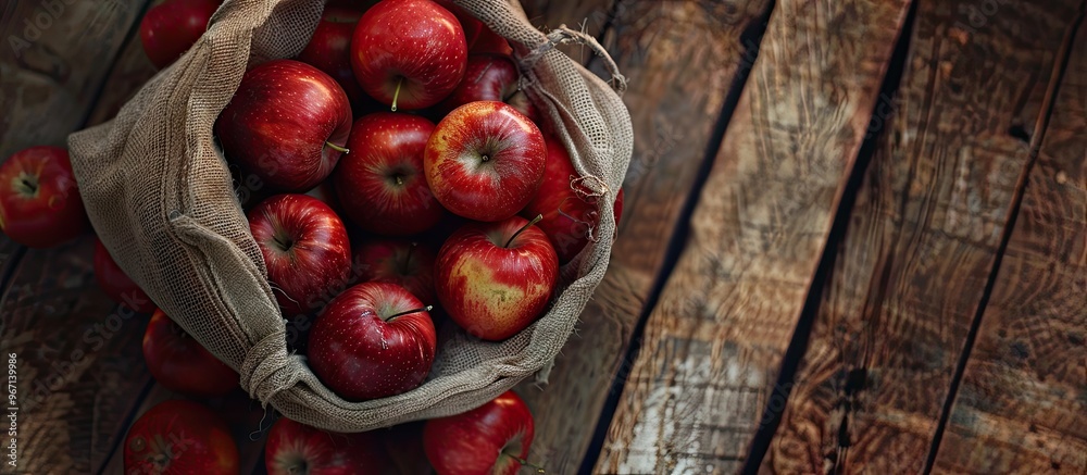 Aufkleber Top view of a wooden background holding freshly arranged red apples in a grid bag perfect for a copy space image