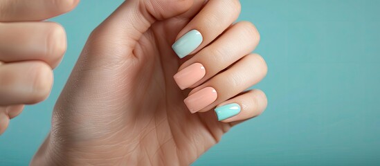 Fototapeta premium Woman displaying a fresh pastel manicure against a blue backdrop with a tranquil spring themed ambiance surrounded by earthy neutral tones providing a simplistic appeal Includes copy space image