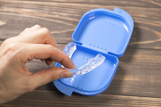 Woman takes Dental splint mouth guard from the box. TMJ splint disorder treatment. Occlusal splint. Prevent bruxism. Mouth guard for TMJ. Teeth protection. Pain in jaw. Teeth grinding.