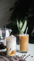 Iced a coffee cup on the glass cup with roasted beans coffee and an Italian moka coffee pot on the wooden table. Vertical photo